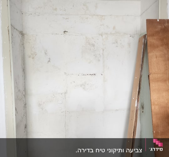 קיר לבן עם סימני צבע ולוחות עץ בצד